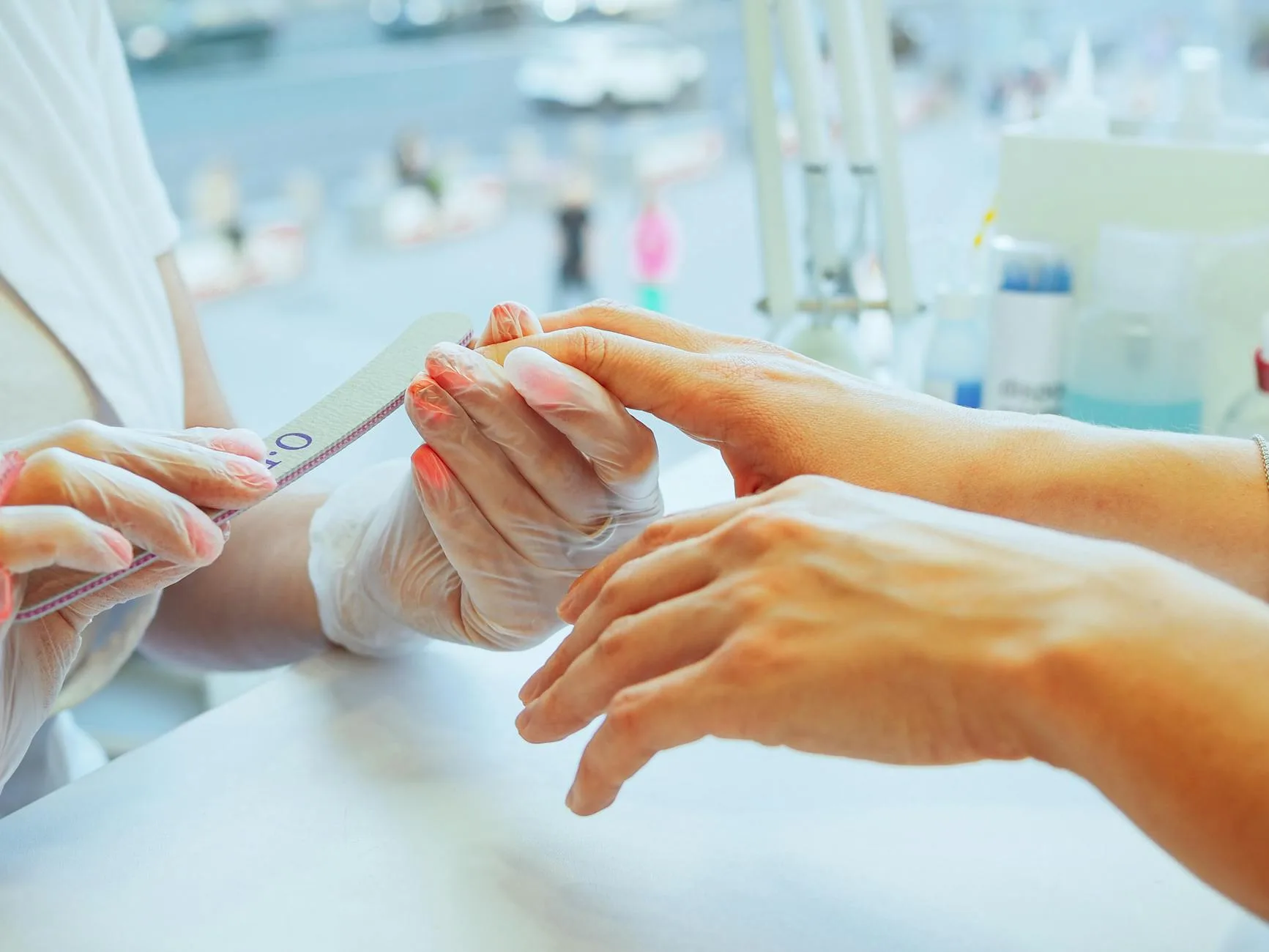 Nail technician filing a client's nails during a manicure